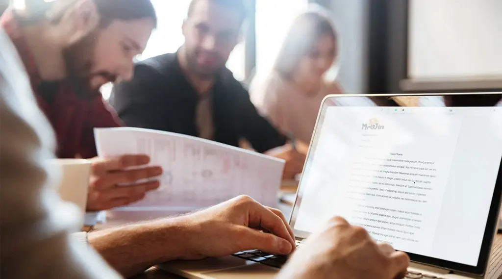 Team of professionals collaborating on betting industry content with laptop and documents.