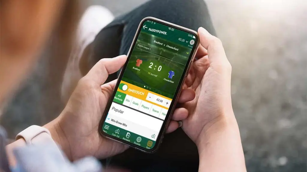 Person using Paddy Power mobile betting app showing live football score and betting options.